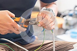 Technician man connecting electric wires with pliers to install new air conditioning, repair service, and install new air