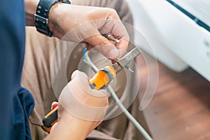 Technician man cutting electrical wires with pliers for installing new air conditioning, repair service, and install new air