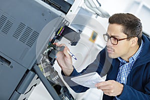 Technician man fixing photo copier