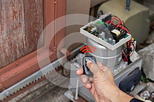 Technician man hand holding the  remote control, testing and checking the function of automatic gate.