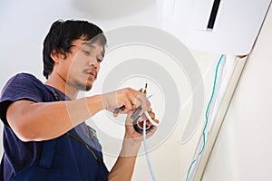 Technician man installing air conditioning in a client house, Electrician mounting the wires into air conditioning unit, Repairman