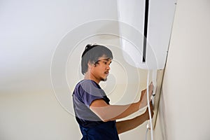 Technician man installing air conditioning in a client house, Young repairman fixing air conditioner unit, Maintenance and