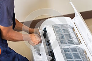 Technician man installing an air conditioning in a client house, Young repairman fixing air conditioner unit, Maintenance and