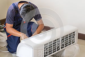 Technician man installing an air conditioning in a client house, Young repairman fixing air conditioner unit, Maintenance and