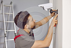 Technician man installing wireless CCTV camera on wall