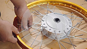 Technician man working motorcycle wheel has spokes weave up on mechanic new steel wheel