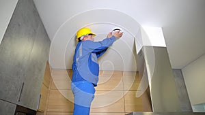 Technician man with yellow helmet checking air diffuser duct in kitchen