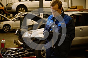 Technician, mechanic in professional uniform with wrench at repair shop. Automobile warranty repair and maintenance concept