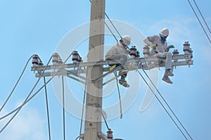 Technician men fixing or repairing broken power line on electric pole, highly dangerous work