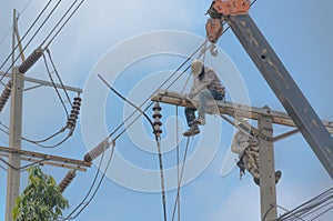 Technician men fixing or repairing broken power line on electric pole, highly dangerous work