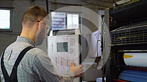 Technician operator checking input and output status on touchscreen front display monitor station in digital printshop