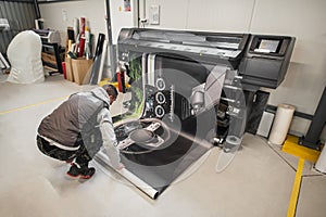 Technician operator works on large premium industrial printer plotter machine