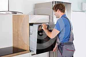 Technician In Overall Installing Oven photo