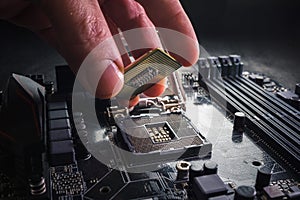 Technician plug in CPU microprocessor to motherboard socket. Workshop background. PC upgrade or repair concept.