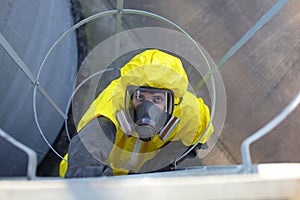 technician in protective uniform going up a metal