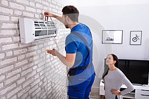 Technician Repairing Air Conditioner With Digital Multimeter