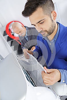 Technician repairing air conditioner on wall