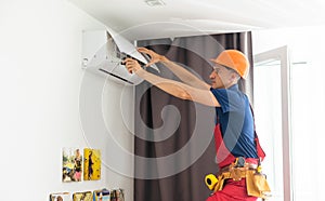 Technician repairing air conditioner on the wall.