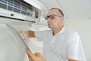 Technician repairing air conditioner on wall