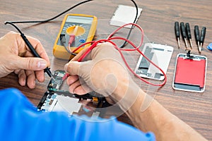 Technician repairing cellphone with multimeter