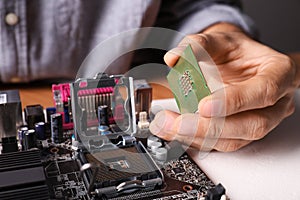 Technician repairing computer motherboard at table, closeup. Electronic device