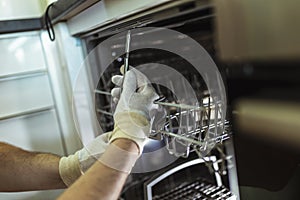 Technician Repairing Dishwasher In Kitchen, close up