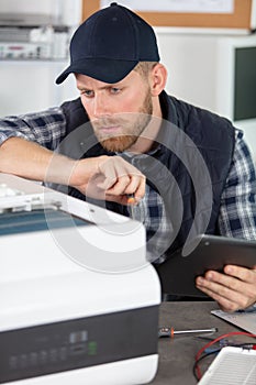 technician repairing printer and holding tablet