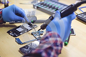 Technician repairing the smartphone`s motherboard in the lab. Showing process of mobile phone repair.