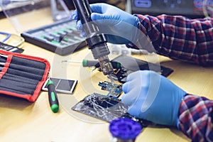 Technician repairing the smartphone`s motherboard in the lab. Showing process of mobile phone repair.