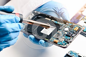 The technician repairing the smartphone`s motherboard in the lab by soldering method. the concept of computer hardware, mobile pho