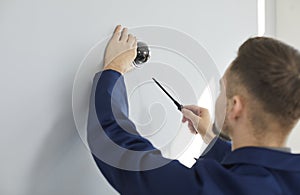 Technician repairing surveillance CCTV dome video camera on wall inside the building