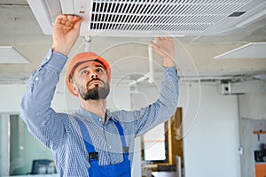 technician service checking and repairing air conditioner indoors