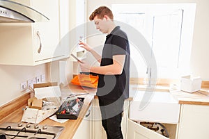 Technician servicing boilerÃÂ in kitchen using tablet computer photo