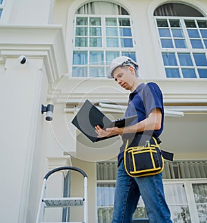 A technician sets up a CCTV camera on the facade of a residential building.