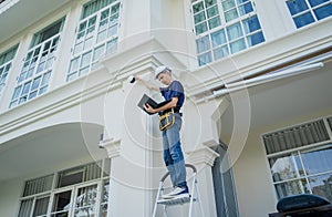 A technician sets up a CCTV camera on the facade of a residential building.