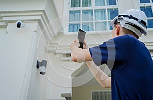 A technician sets up a CCTV camera on the facade of a residential building.