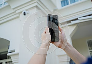 A technician sets up a CCTV camera on the facade of a residential building.