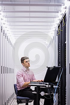 Technician sitting on swivel chair using laptop to diagnose servers photo