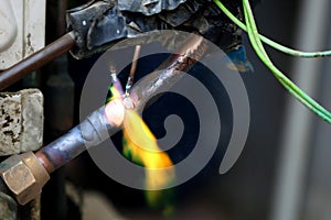 Technician are soldering a coil with copper in order to fix leakage of air compressor. This is a oil and piping problem of air-con