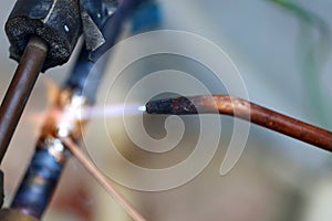 Technician are soldering a coil with copper in order to fix leakage of air compressor. This is a oil and piping problem of air-con