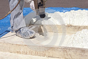 Technician spraying foam insulation using Plural Component Spray Gun.