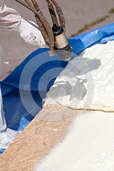Technician spraying foam insulation using Plural Component Spray Gun.