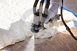 Technician spraying foam insulation using Plural Component Spray Gun. photo