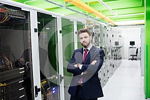 Technician standing with arms crossed in a server room