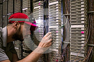 Technician switches the wires to the cross panel in the server room. The specialist shines a flashlight on the IP telephony patch