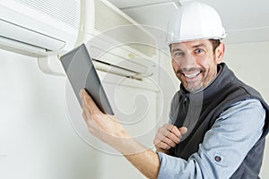 Technician with tablet by air conditioning unit