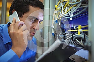 Technician talking on mobile phone while analyzing server