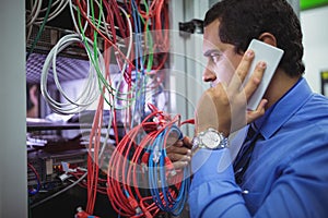 Technician talking on mobile phone while checking cables