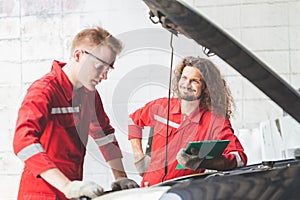 Technician team checking modern car at garage, Car mechanic with a checklist, Mechanics in uniform are working in auto service