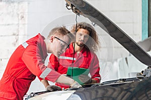 Technician team checking modern car at garage, Young Caucasian car mechanic with a checklist, Mechanics in uniform are working in